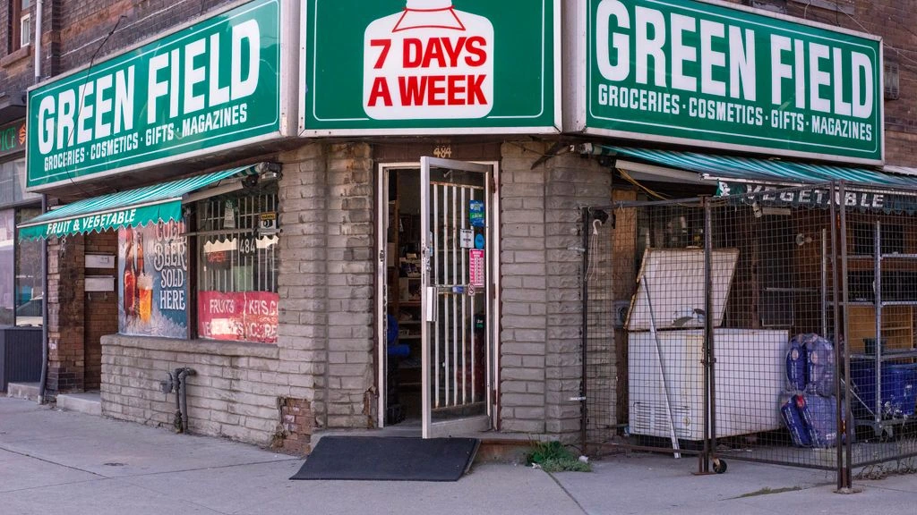 A shuttered corner grocery store with a For Lease sign in the window.